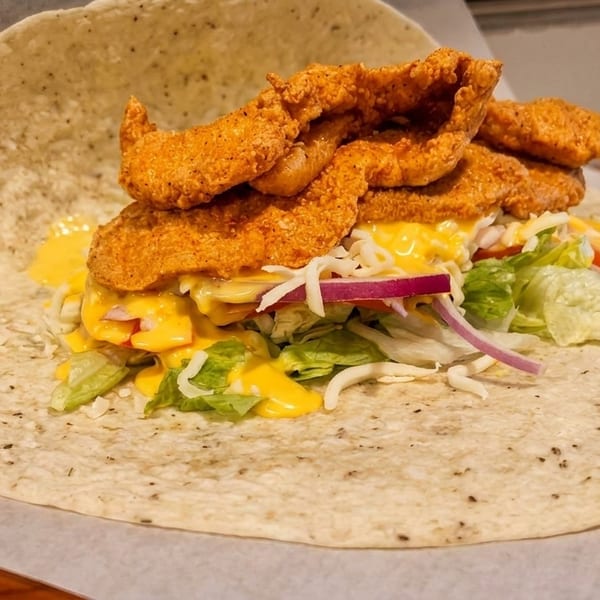 Crispy fried chicken tenders, lettuce, cheese, and red onion on a tortilla wrap.